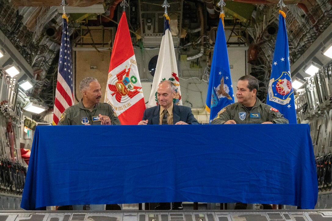 U.S. Air Force Brigadier General David Cochran, West Virginia National Guard Assistant Adjutant General and commander of the West Virginia Air National Guard, David Delmonaco, 12th Air Force (Air Forces Southern) representative, and Lt. Gen. Carlos Chavez, the Peruvian Air Force Chief of Staff, sign an agreement of future engagements during a trilateral agreement signing ceremony in a hangar at the 167th Airlift Wing, Shepherd Field, Martinsburg, West Virginia, June 9, 2023.