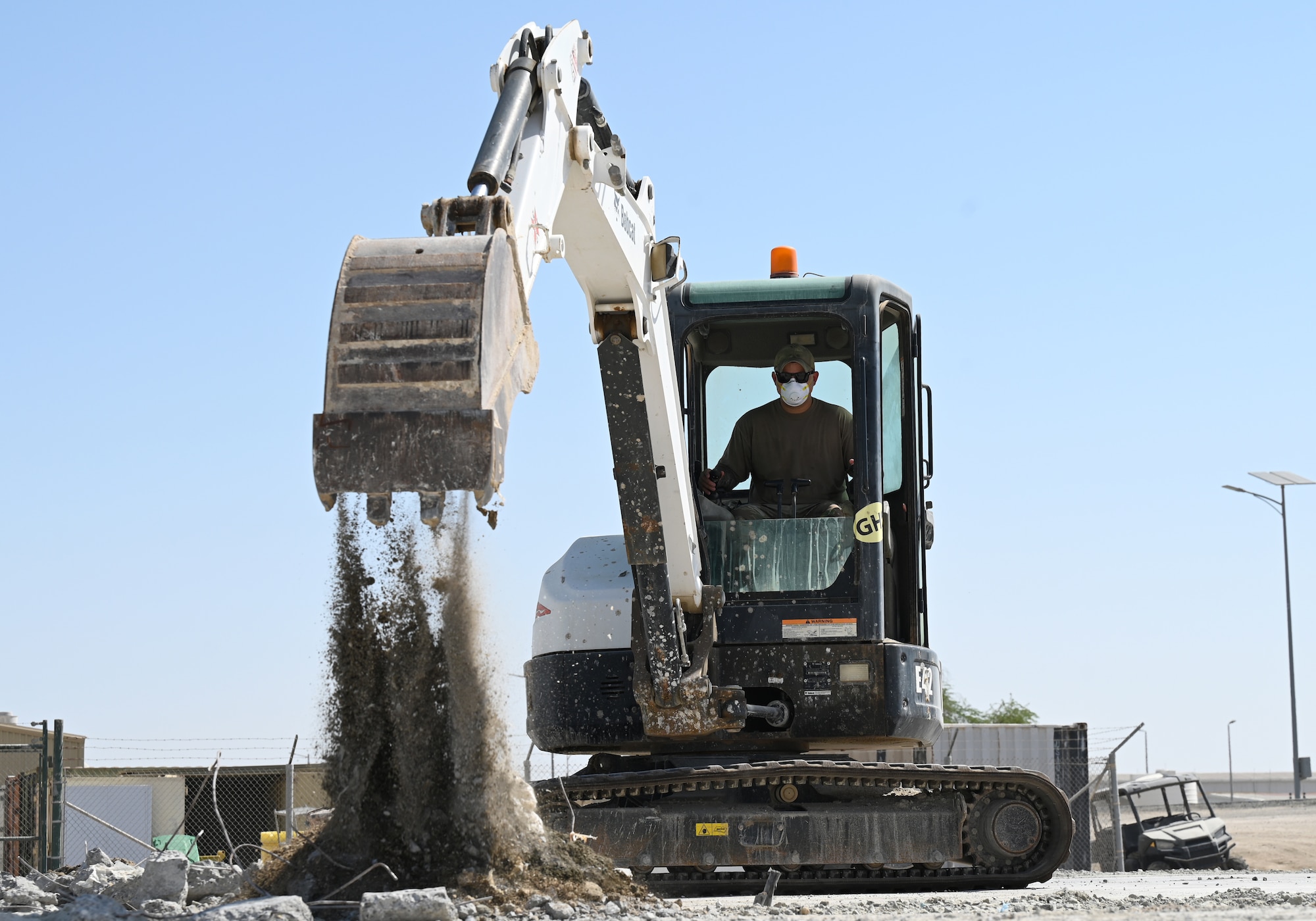 A photo of an Airmen digging out a crater with an excavator.