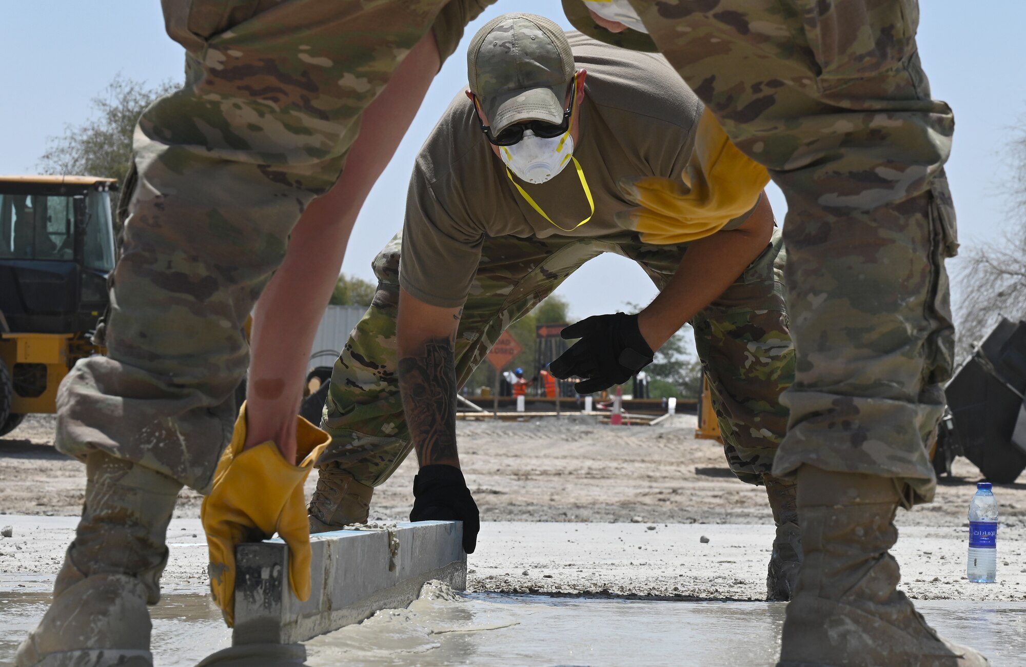 A photo of two Airmen smoothing out concrete.