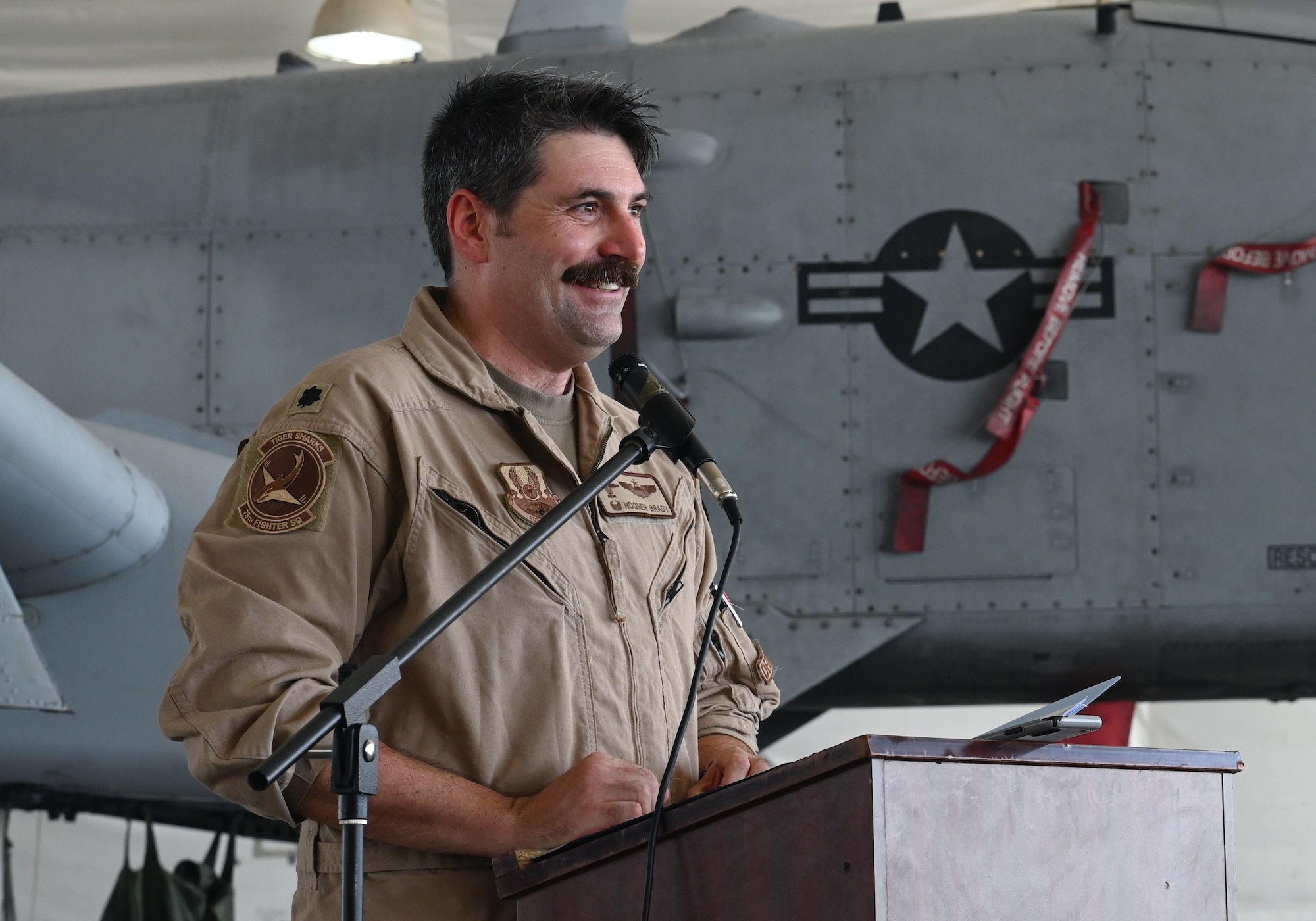 A photo of an Airman speaking at a podium.