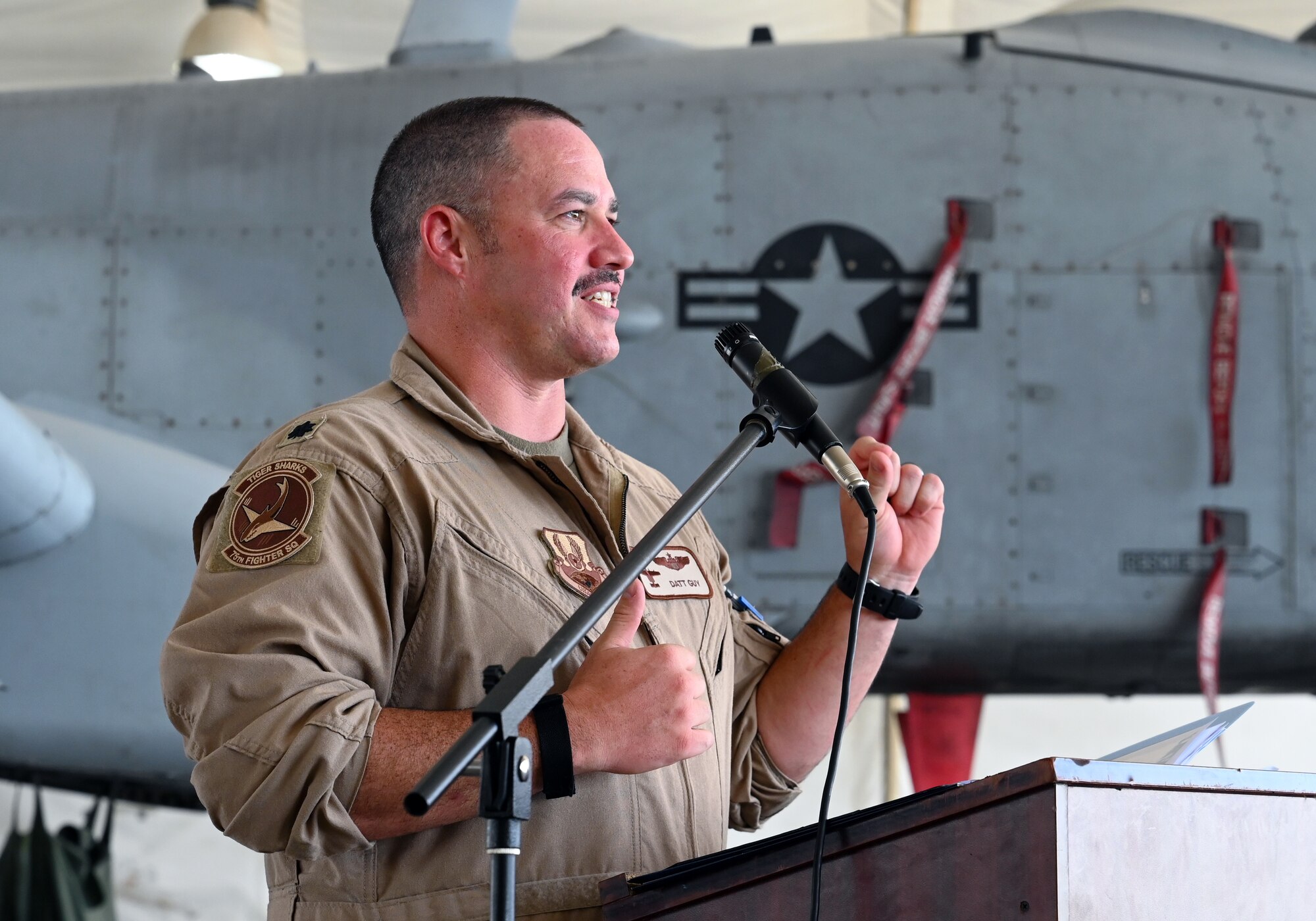 A photo of an Airman speaking at a podium.