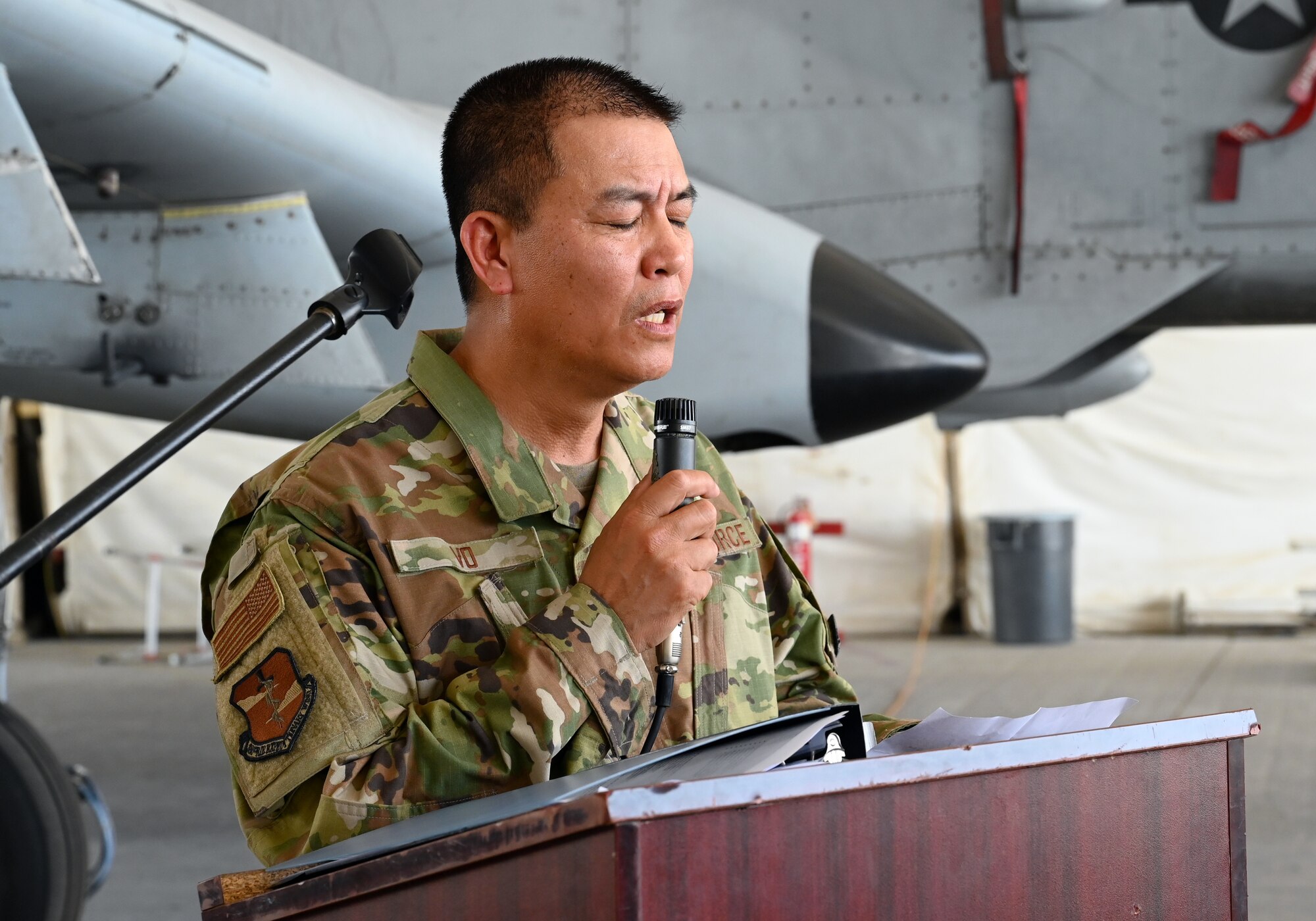 A photo of an Airman providing the invocation at a podium.