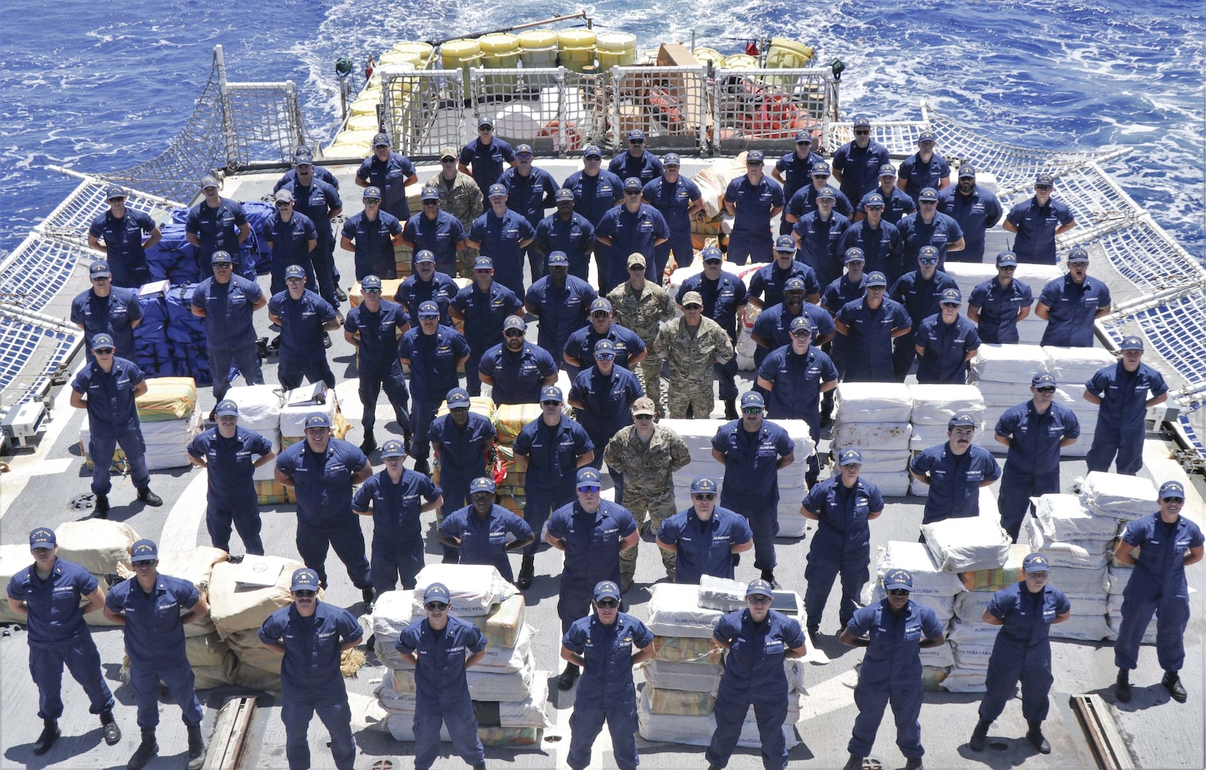 The crew of Coast Guard Cutter Bear (WMEC 901) stands amongst 14,153 pounds of interdicted narcotics at Miami, Florida, June 16, 2023.