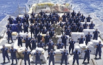 The crew of Coast Guard Cutter Bear (WMEC 901) stands amongst 14,153 pounds of interdicted narcotics at Miami, Florida, June 16, 2023.