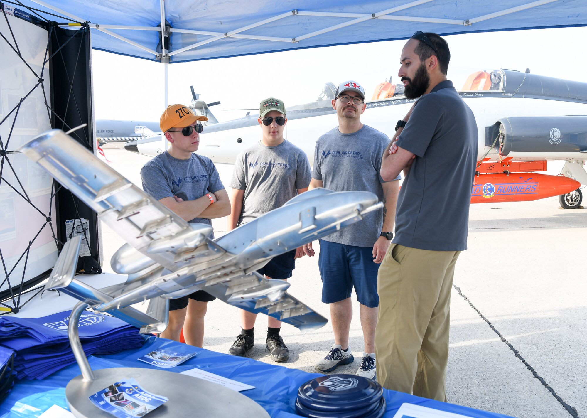 Group talking with scale model of aircraft in foreground