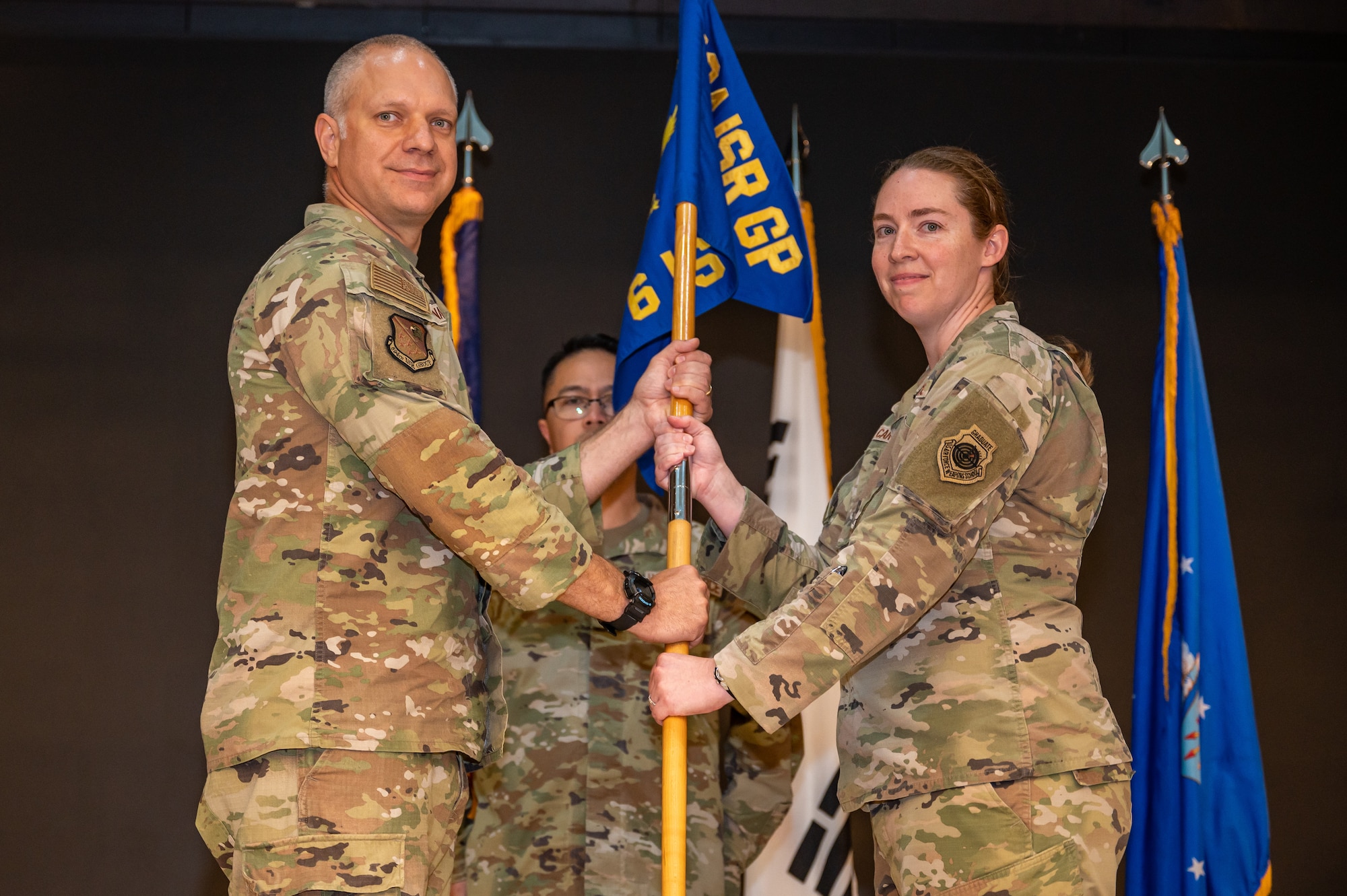 U.S. Air Force Lt. Col. Jarrod Knapp, left, 694th Intelligence, Surveillance, and Reconnaissance group deputy commander, receives the guidon from Lt. Col. Laura Carter, right, 6th Intelligence Squadron outgoing commander, at Osan Air Base, Republic of Korea, June 14, 2023. In a change of command ceremony, the guidon symbolizes the transfer of command and the authority and responsibility associated with it. (U.S. Air Force photo by Senior Airman Thomas Sjoberg)
