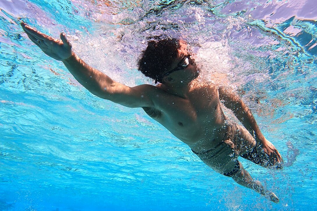 A Marine swims in a pool.