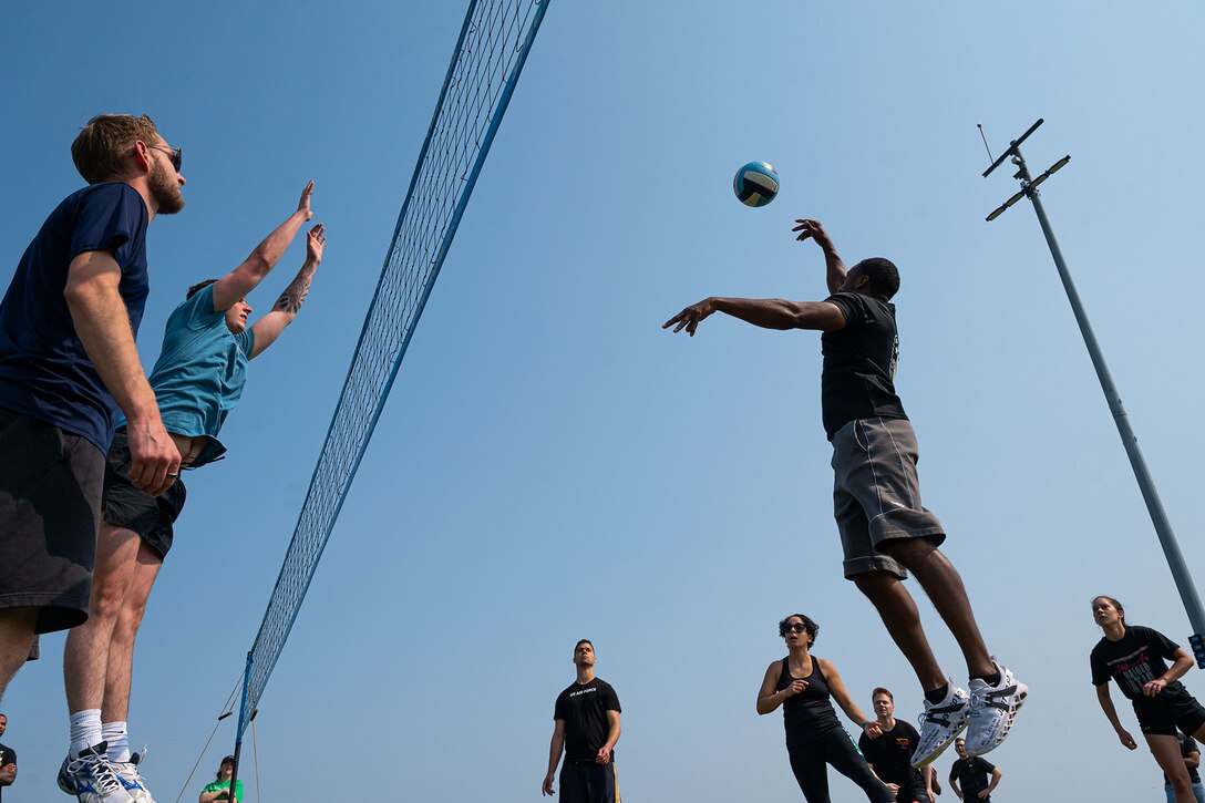 Airmen leap on both sides of a volleyball net.