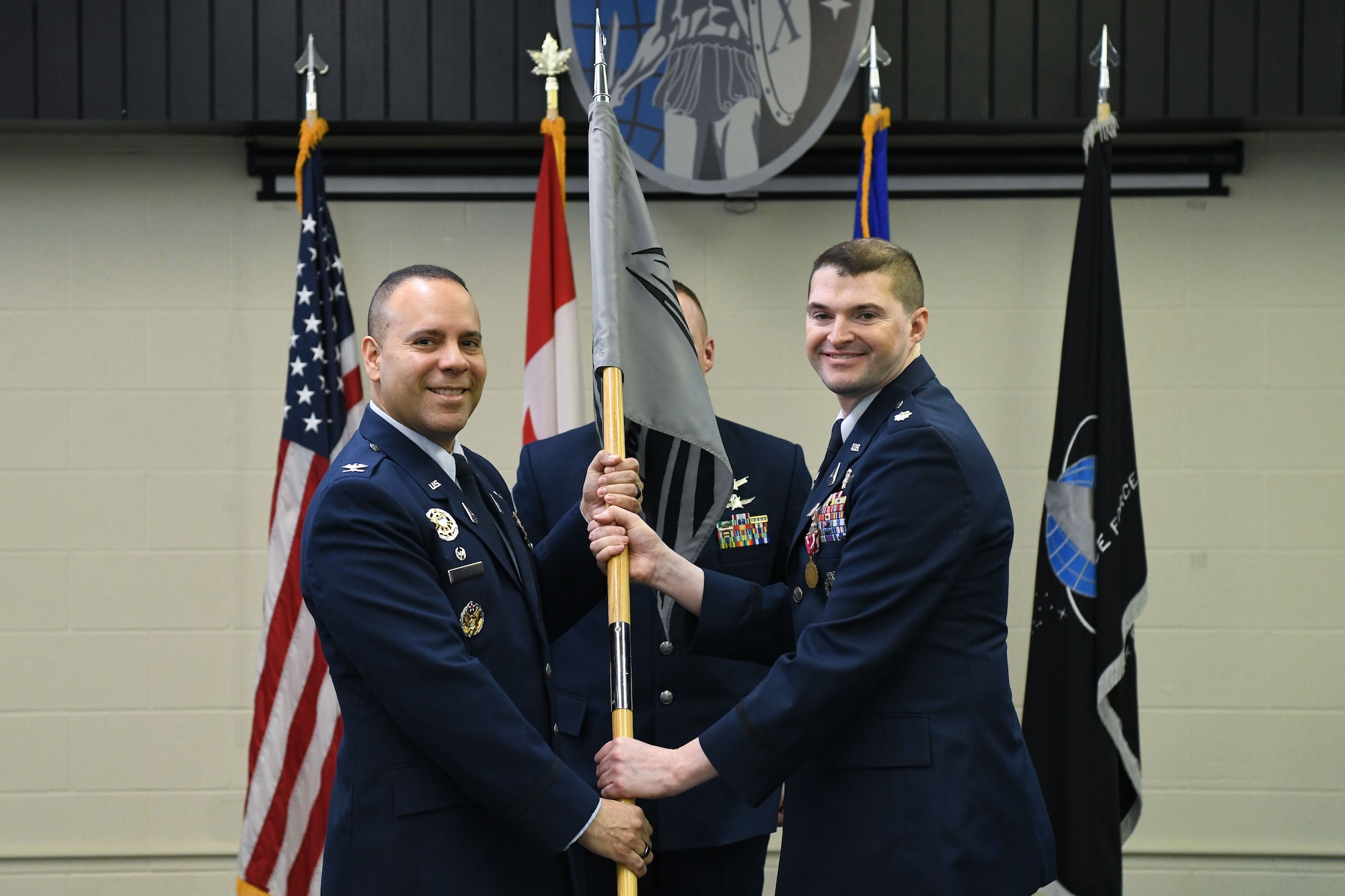 Two men in blue suits hold flag.