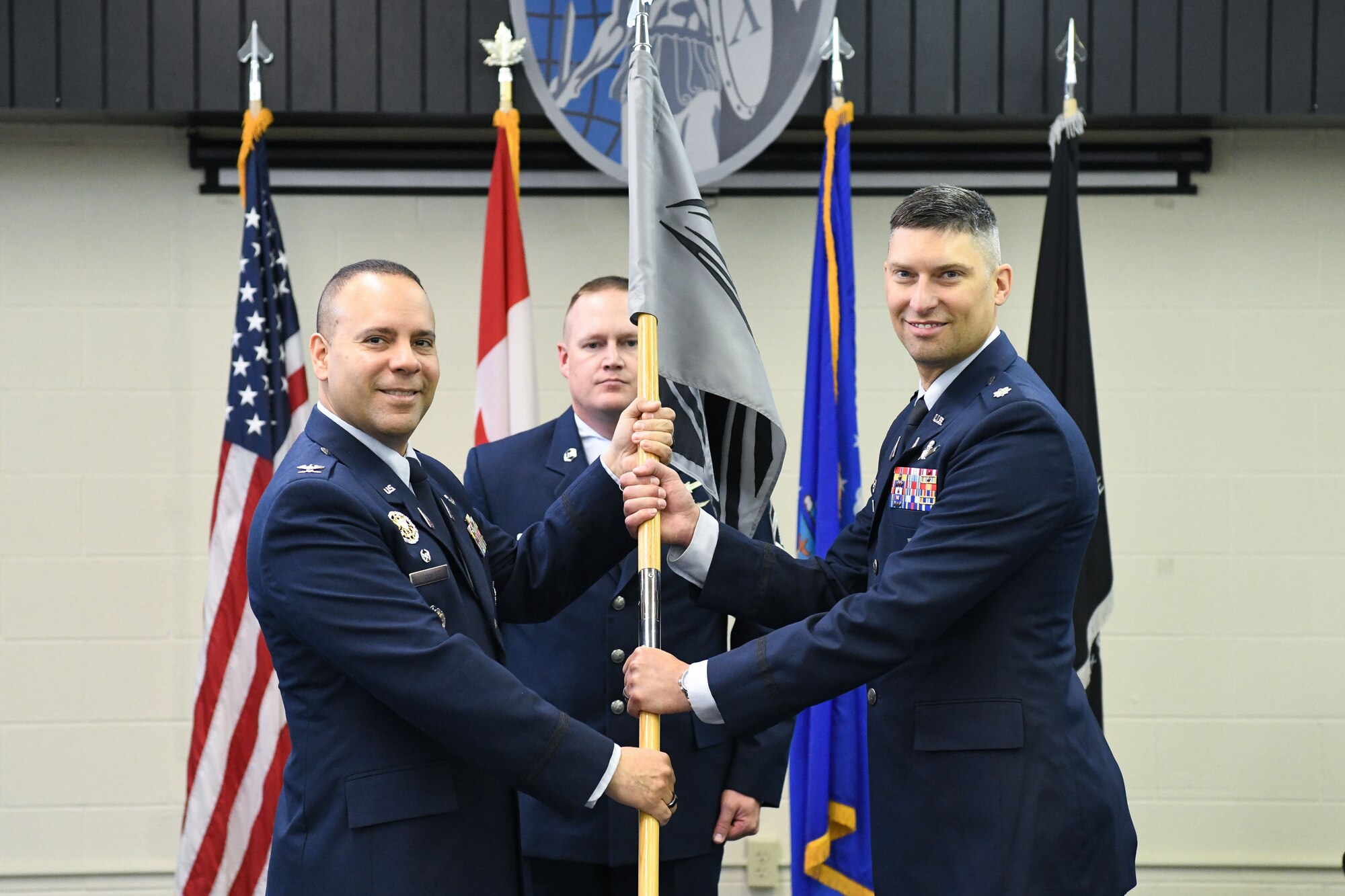 Two men in blue suits hold flag.