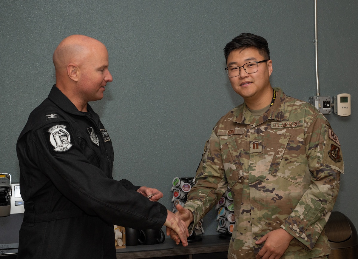 U.S. Air Force Col. David Berkland, 354th Fighter Wing commander, left, coins Capt. Sung Woo Suh, 80th Fighter Generation Squadron Director of Operations at Eielson Air Force Base Alaska, June 9, 2023. While deployed to Eielson in support of RED FLAG-Alaska, Suh, along with the 80th FGS production supervisor Master Sgt. Carleton Kennedy, were recognized for saving an infant, father and dog from drowning and hypothermia when their kayak capsized in Chena Lake Recreation Area, Alaska on June 3, 2023. (U.S. Air Force photo by Staff Sgt. Danielle Sukhlall)