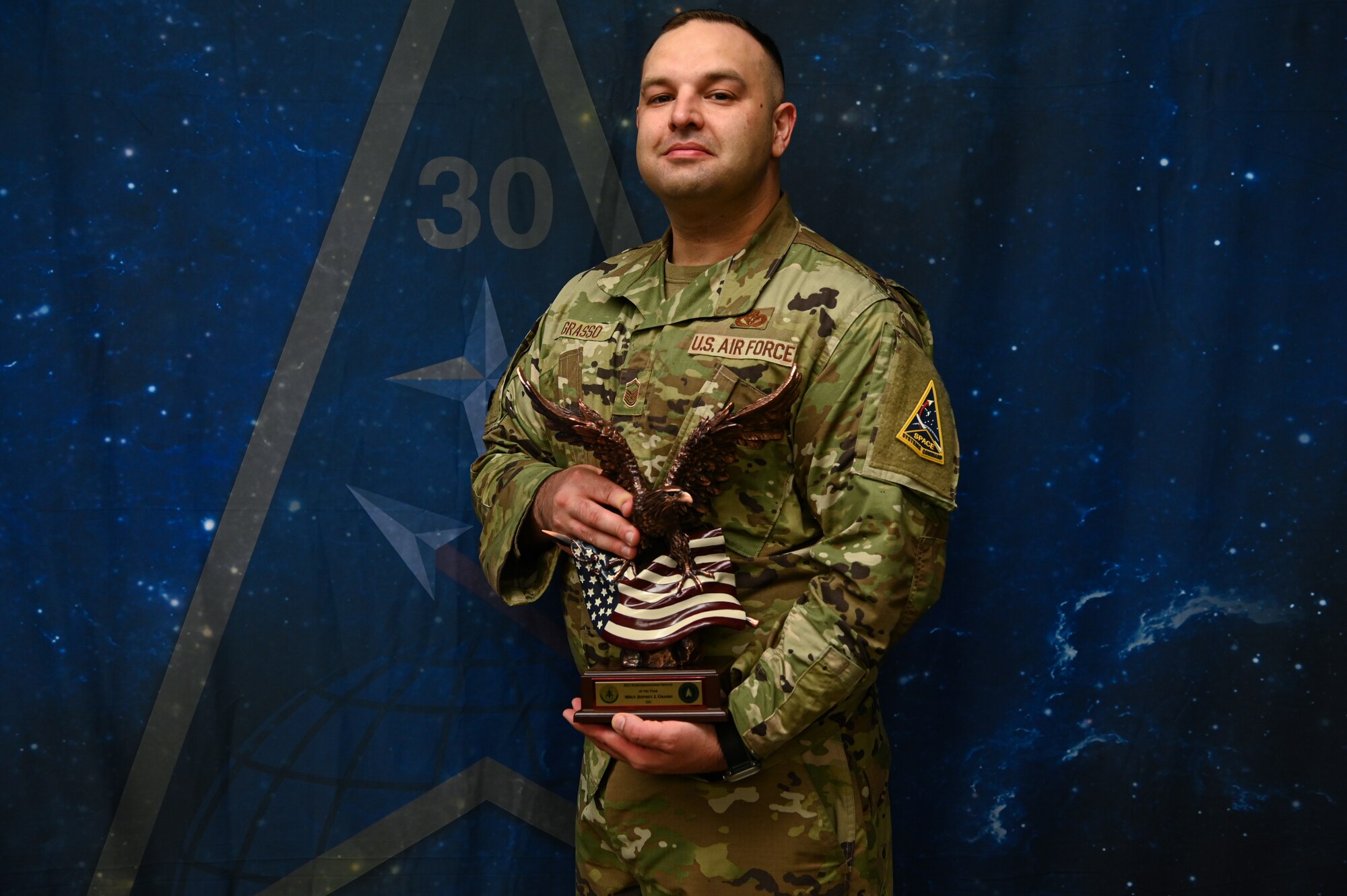 Master Sgt. Jeffrey Grasso, a structures craftsman from the 30th Civil Engineer Squadron and a Space Launch Delta 30 first sergeant, stands with his Air Force Materiel Command 2022 NCO of the Year award. Grasso also earned the Space System Command 2022 NCO of the Year. These achievements led to his nomination for the Department of the Air Force's 12 Outstanding Airmen of the Year program. (U.S. Space Force photo by Airman First Class Kadielle Shaw)