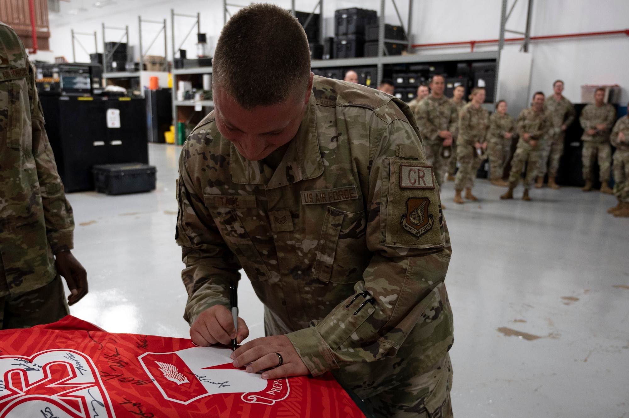 U.S. Air Force Staff Sgt. Lucas Tate, unit training manager assigned to the 36th Contingency Response Squadron, signs the Linebacker of the Week jersey at Andersen Air Force Base, Guam, June 14, 2023. The Team Andersen Linebacker of the Week recognizes outstanding enlisted, officer, civilian and total force personnel who have had an impact on achieving Team Andersen’s mission, vision and priorities. (U.S. Air Force photo by Airman 1st Class Emily Saxton)