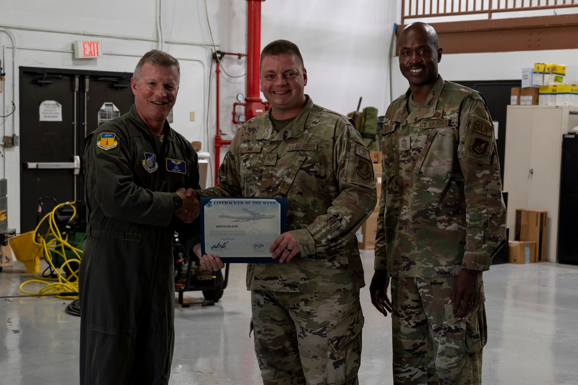 U.S. Air Force Staff Sgt. Lucas Tate, unit training manager assigned to the 36th Contingency Response Squadron, receives the Linebacker of the Week Award from U.S. Air Force Brig. Gen. Paul Fast, commander of the 36th Wing, and U.S. Air Force Chief Master Sgt. Nicholas Taylor, the command chief of the 36th Wing, at Andersen Air Force Base, Guam, June 14, 2023. The Team Andersen Linebacker of the Week recognizes outstanding enlisted, officer, civilian and total force personnel who have had an impact on achieving Team Andersen’s mission, vision and priorities. (U.S. Air Force photo by Airman 1st Class Emily Saxton)