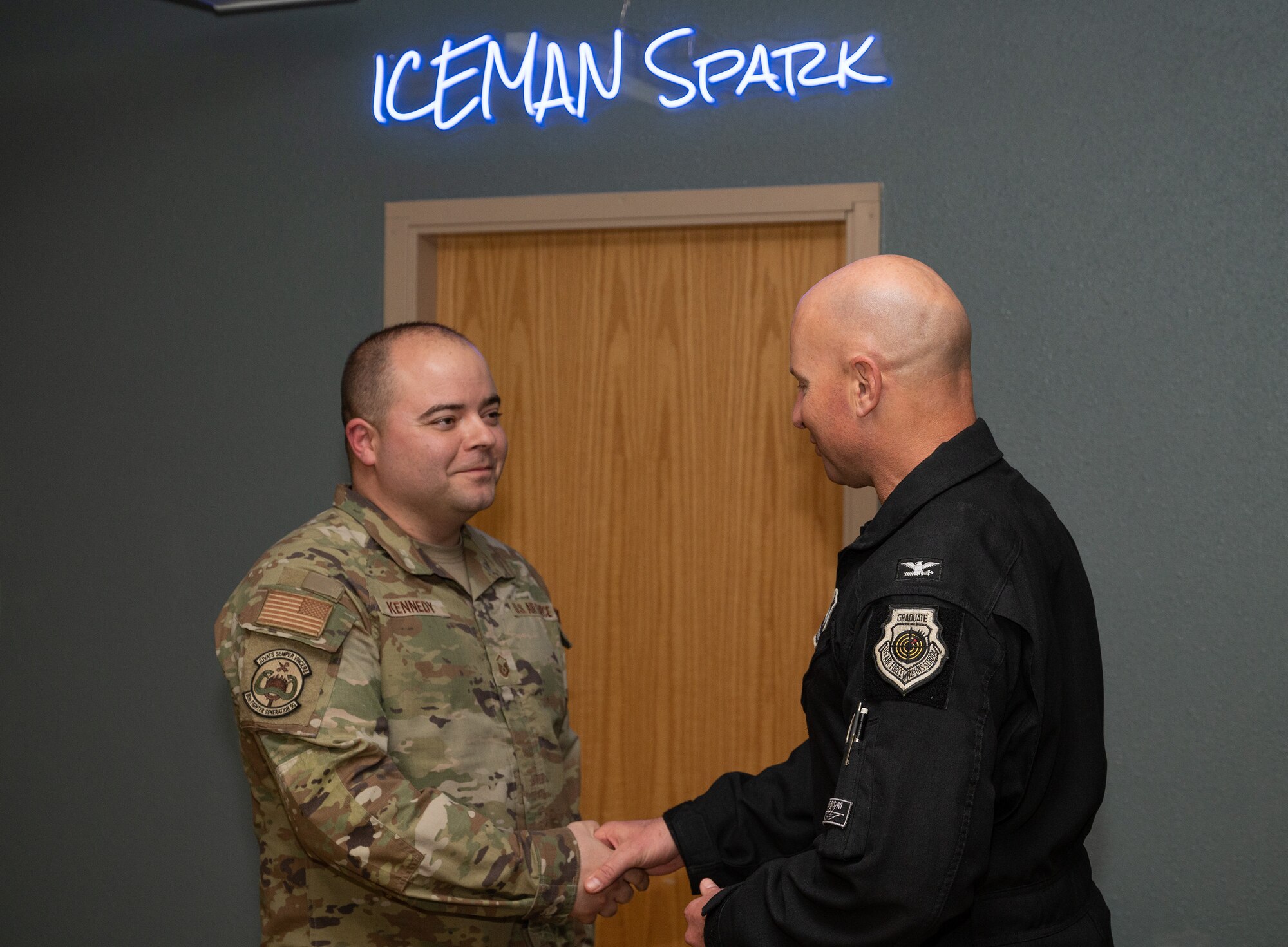 U.S. Air Force Col. David Berkland, 354th Fighter Wing commander, right, coins Master Sgt. Carleton Kennedy, 80th Fighter Generation Squadron production supervisor, at Eielson Air Force Base Alaska, June 9, 2023. While deployed to Eielson in support of RED FLAG-Alaska, Kennedy, along with the 80th FGS Director of Operation Capt. Sung Woo Suh, were recognized for saving an infant, father and dog from drowning and hypothermia when their kayak capsized in Chena Lake Recreation Area, Alaska on June 3, 2023. (U.S. Air Force photo by Staff Sgt. Danielle Sukhlall)