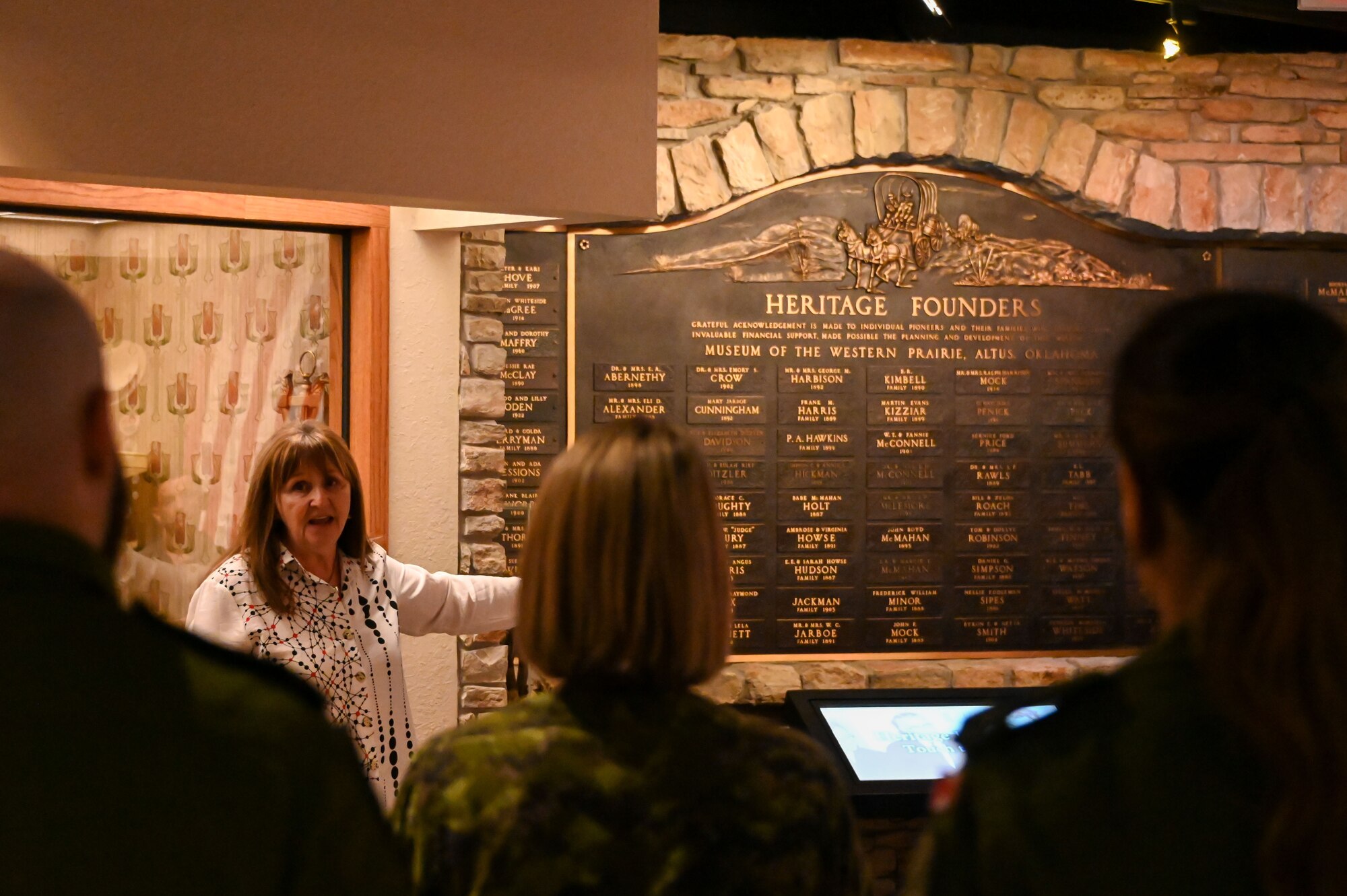 Jennie Buchanan, Museum of the Western Prairie director, shares Oklahoma history information during a tour for 97th Training Squadron international students at the museum in Altus, Oklahoma, May 19, 2023. The plaque highlighted over 20 names of Altus’ heritage founders and their contributions to the community. (U.S. Air Force photo by Senior Airman Kayla Christenson)
