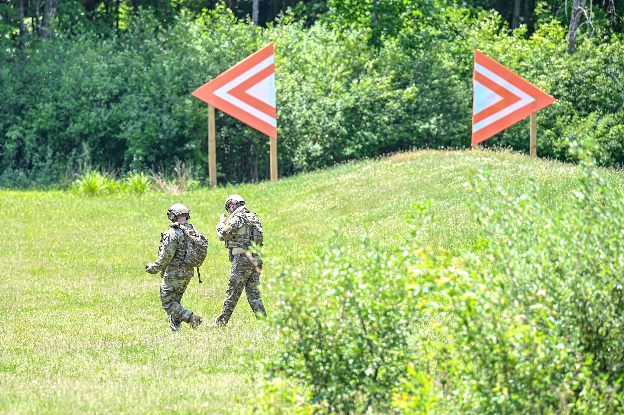 Tech. Sgt. Allen Russell, an Integrated Defense Leadership Course cadre member assigned to the 910th Security Forces Squadron, Youngstown Air Reserve Station, Ohio, and Senior Master Sgt. Jason Knepper, Air Force Reserve Command Security Forces training manager, walk toward a bunker to detonate live grenades on May 31, 2023, at Camp James A. Garfield Joint Military Training Center, Ohio.