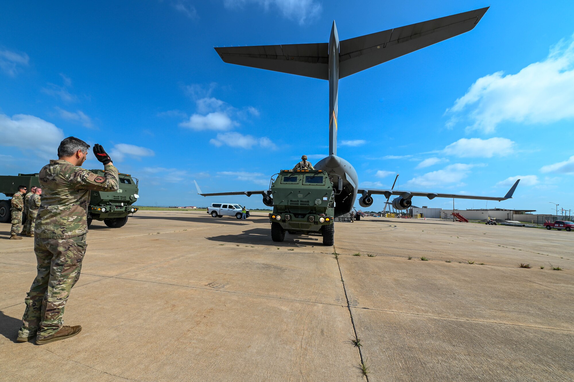 U.S. Air Force Tech. Sgt. Jose Deleon, 58th Airlift Squadron instructor loadmaster, directs a M142 High Mobility Artillery Rocket System (HIMARS) onto a C-17 Globemaster III at Lawton Regional Airport, Oklahoma, June 14, 2023. The HIMARS is capable of achieving ranges of 70-plus kilometers, attacking the target with low-collateral damage, enabling danger-close fires in support of friendly troops in contact, as well as engaging high-valued point targets in open, urban, and complex environments. (U.S. Air Force photo by Senior Airman Kayla Christenson)
