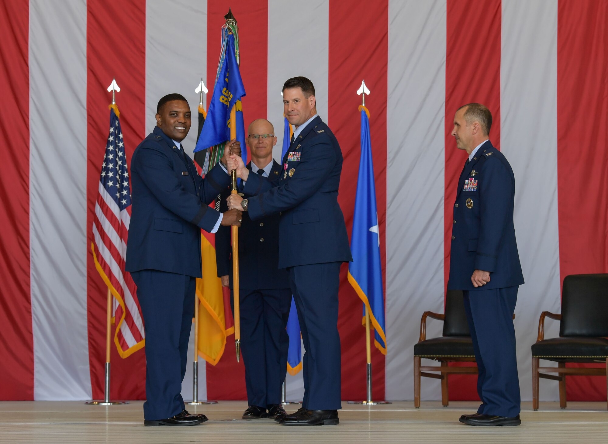 U.S. Air Force Col. Sean Finnan, 86th Operations Group out-going commander, middle, passes the 86th OG guidon to Brig. Gen. Otis C. Jones, 86th Airlift Wing commander, left, during the 86th OG change of command ceremony at Ramstein Air Base, Germany, June 15, 2023. Finnan is retiring after serving 25 years in the Air Force. (U.S. Air Force photo by Airman Trevor Calvert)