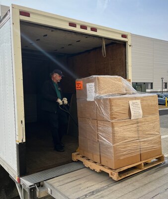 Man loading boxes of office supplies onto a box truck