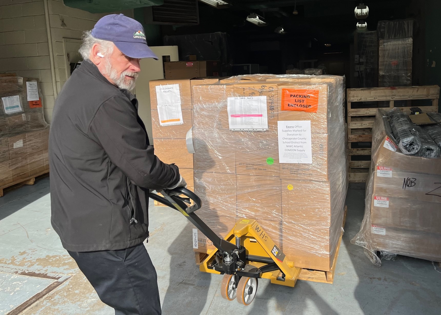 Man pulls a hand truck of boxes of office supplies
