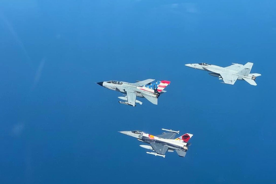 Aircraft fly in formation at sea.