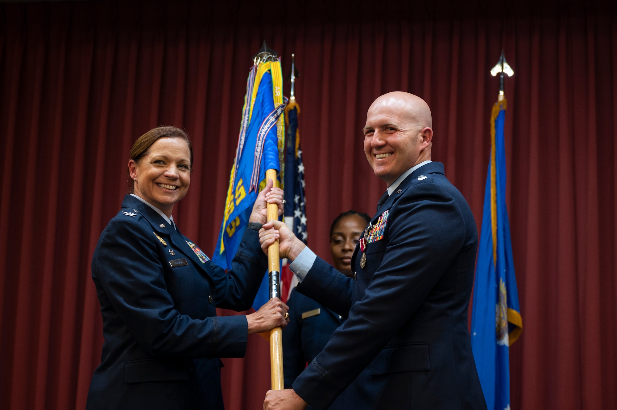 A man passes a guidon to a woman.