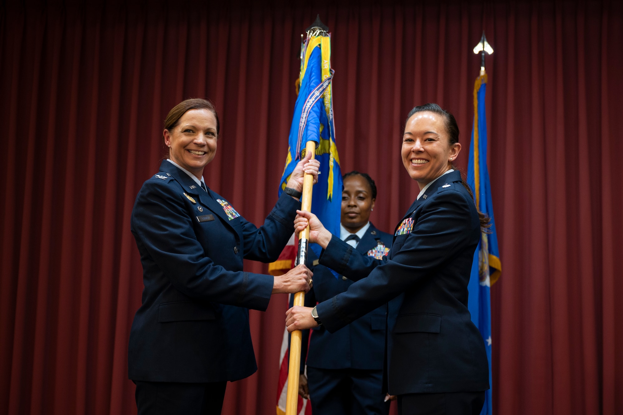 A woman passes a guidon to another woman.