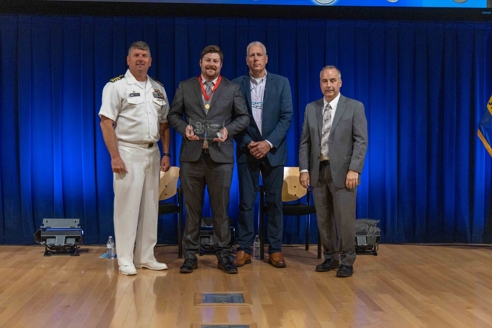 Naval Surface Warfare Center, Carderock Division's Commanding Officer Capt. Matthew Tardy (left), Technical Director Larry Tarasek (right) and Michael Brown (second to right), the Naval Architecture and Engineering Department Head, present the Capt. Harold E. Saunders Award for Exemplary Technical Management to Jayson Geiser, the Submarine Propulsor Production Manager in Carderock’s Advanced Propulsor Management Office, during Carderock's Magnificent Eight Award ceremony in West Bethesda, Md., on June 13. (U.S. Navy photo by Aaron Thomas)