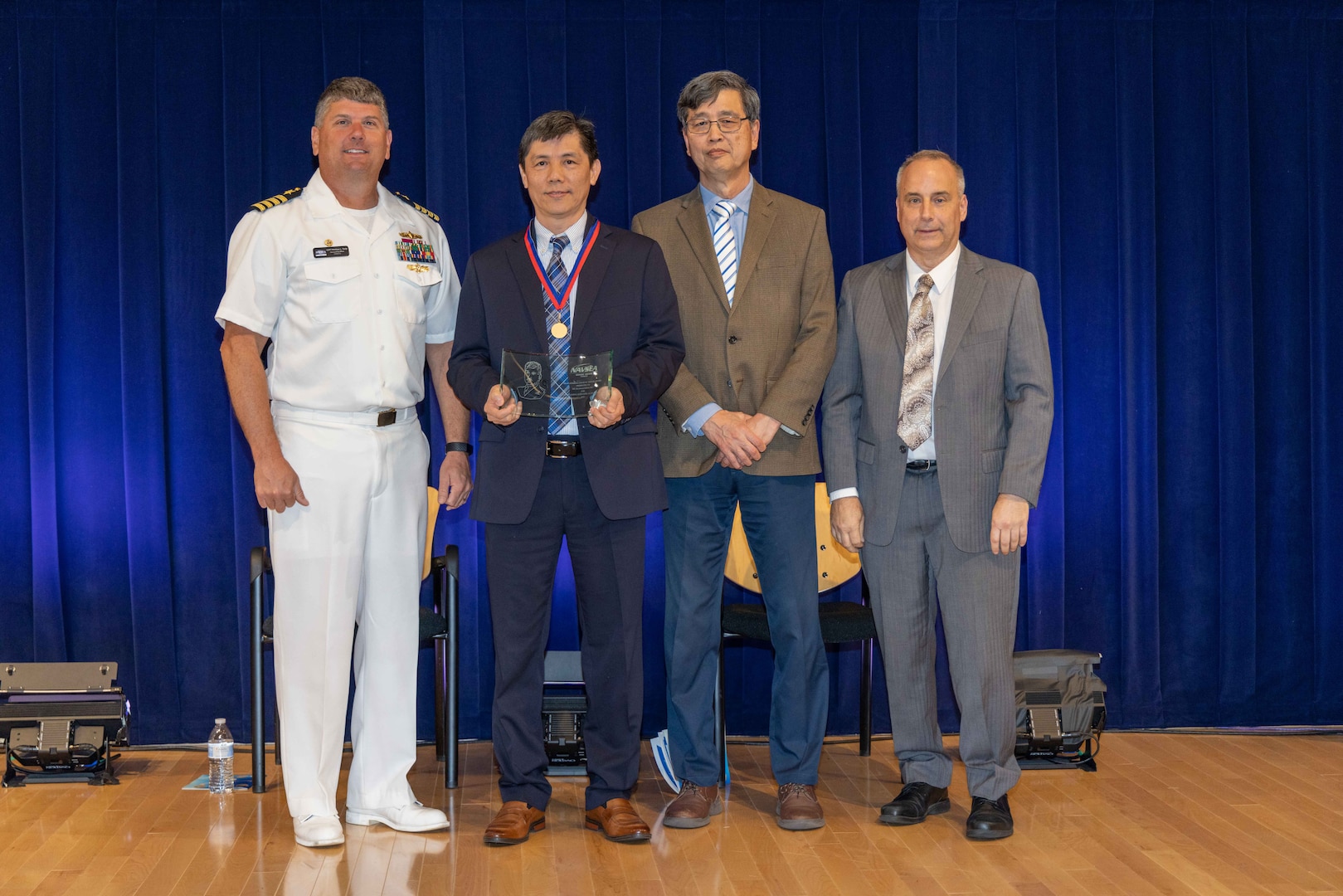 Naval Surface Warfare Center, Carderock Division's Commanding Officer Capt. Matthew Tardy (left), Technical Director Larry Tarasek (right) and Dr. Paul Shang (second to right), the Signatures Department Head, present the Rear Adm. David W. Taylor Award for Outstanding Scientific Achievement to Dr. Kuangcheng Wu, computational methods lead in Carderock’s Structural Acoustics Branch, during Carderock's Magnificent Eight Award ceremony in West Bethesda, Md., on June 13. (U.S. Navy photo by Aaron Thomas)