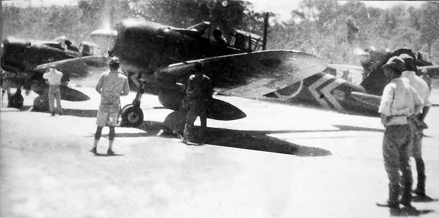 These A6M3 Model 22 Zeros are from the 582nd Kokutai, a fairly large organization that could include as many as 27 aircraft, nine each in individual Chutais (Japanese individual unit organization was quite different from American examples). Their pilots are warming up their fighters’ engines before launching on a long-range mission against targets in the Solomons on June 16, 1943. Along with a 72-gallon center-line drop tank, the Model 22 also included additional 12-gallon fuel tanks in the fighter’s rounded wing tips, giving this Zero the greatest range of any of the many models of the Zero. Note the command chevrons on the first Zero’s rear fuselage.