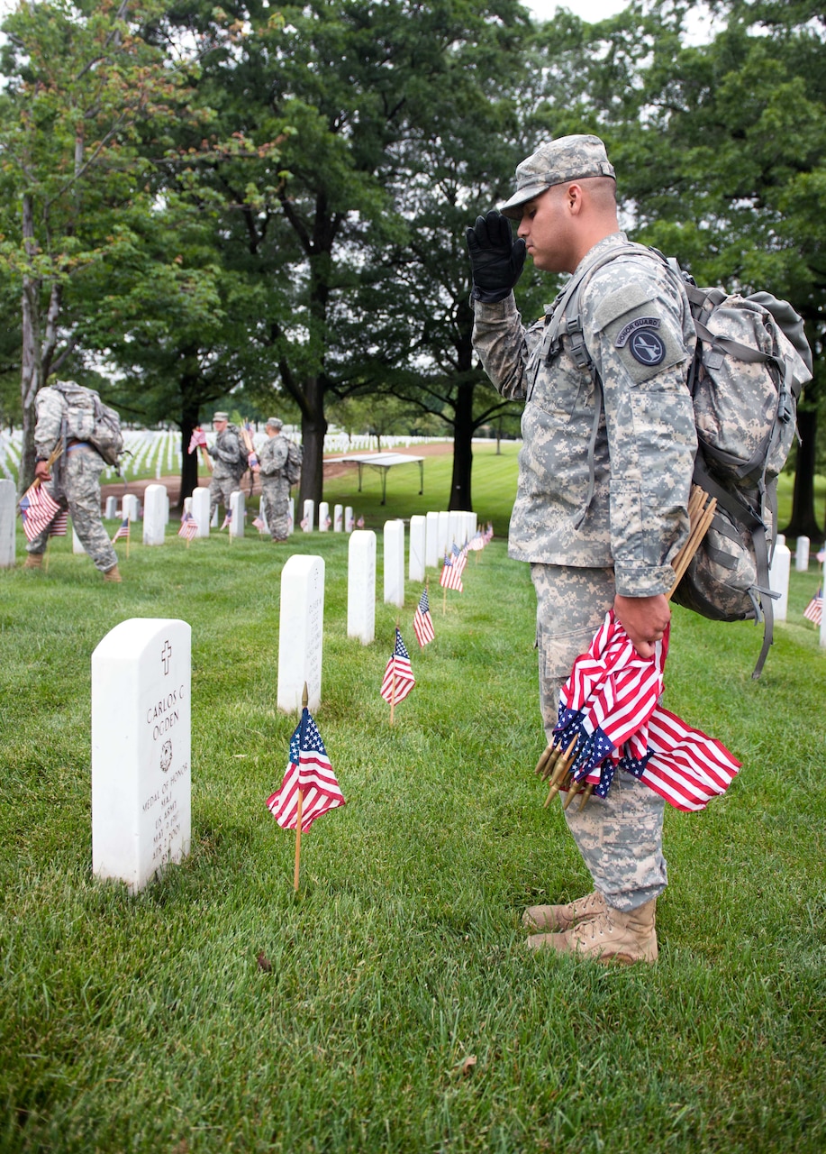 A soldier salutes a headstone at Arlington National Cemetery.