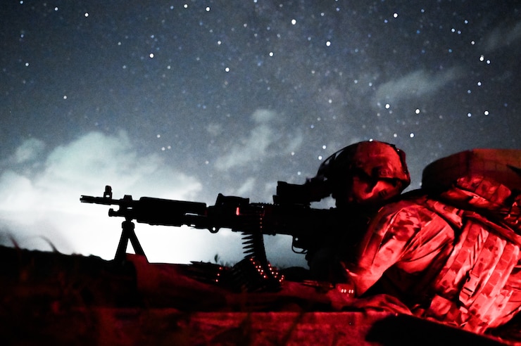 An Airman lays in the prone position with his weapon in low light conditions