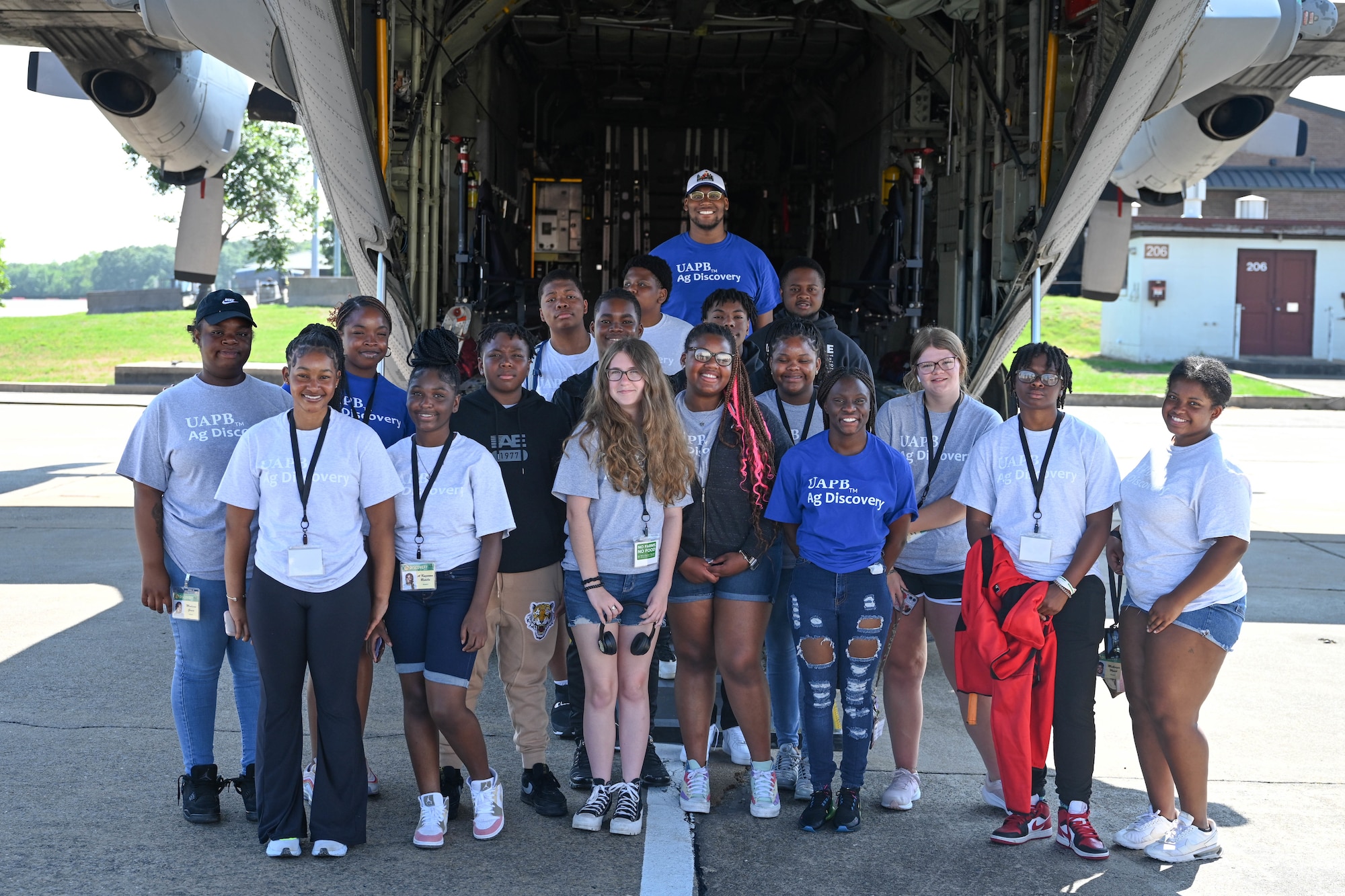 A group of teenagers pose for a photo in front of an aircraft