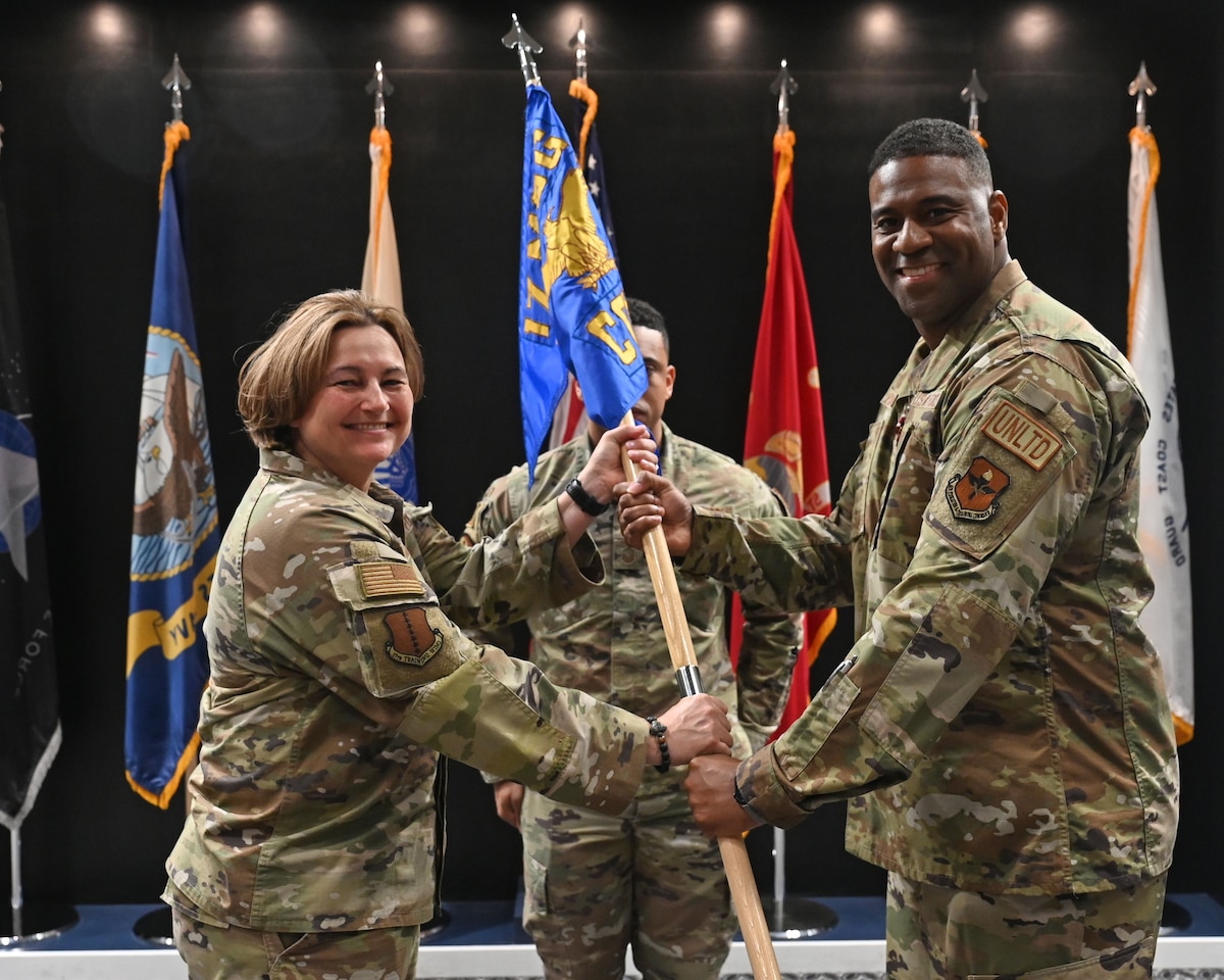U.S. Air Force Col. Angelina Maguinness, 17th Training Wing commander, takes the guidon from Maj. Ivan Pinder-bey, outgoing 17th Contracting Squadron commander, during the change of command ceremony at the Powell Event Center, Goodfellow Air Force Base, Texas, June 21, 2023. Passing the guidon represents the transfer of leadership responsibilities to the next commander. (U.S. Air Force photo by Airman 1st Class Zach Heimbuch)