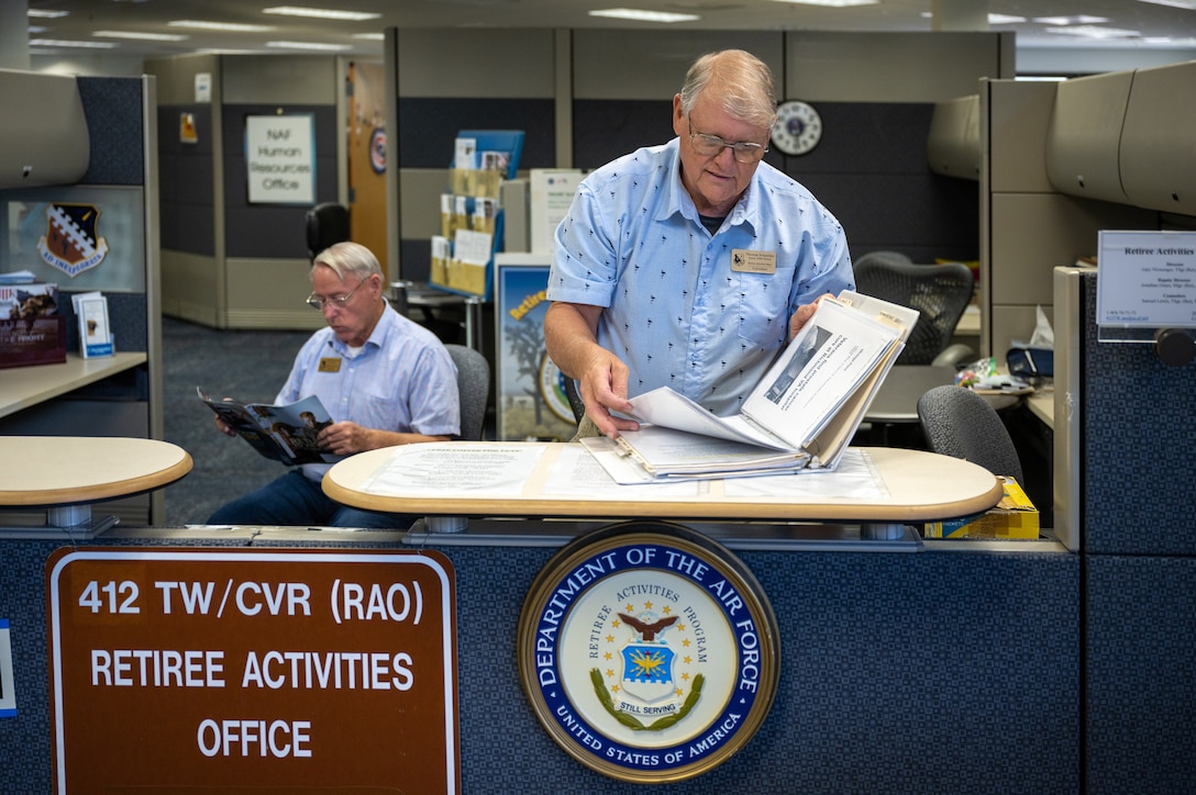 Gary Niswonger, Director, Retiree Activities Office and Thomas Schamber, Volunteer, Retiree Activities Office go through retiree documents in Building 3000. The transition from physical to digital ID cards for civilian retirees is set to start immediately, with full implementation across the DOD planned by June 2025. (U.S. Air Force photo by Harley Huntington)