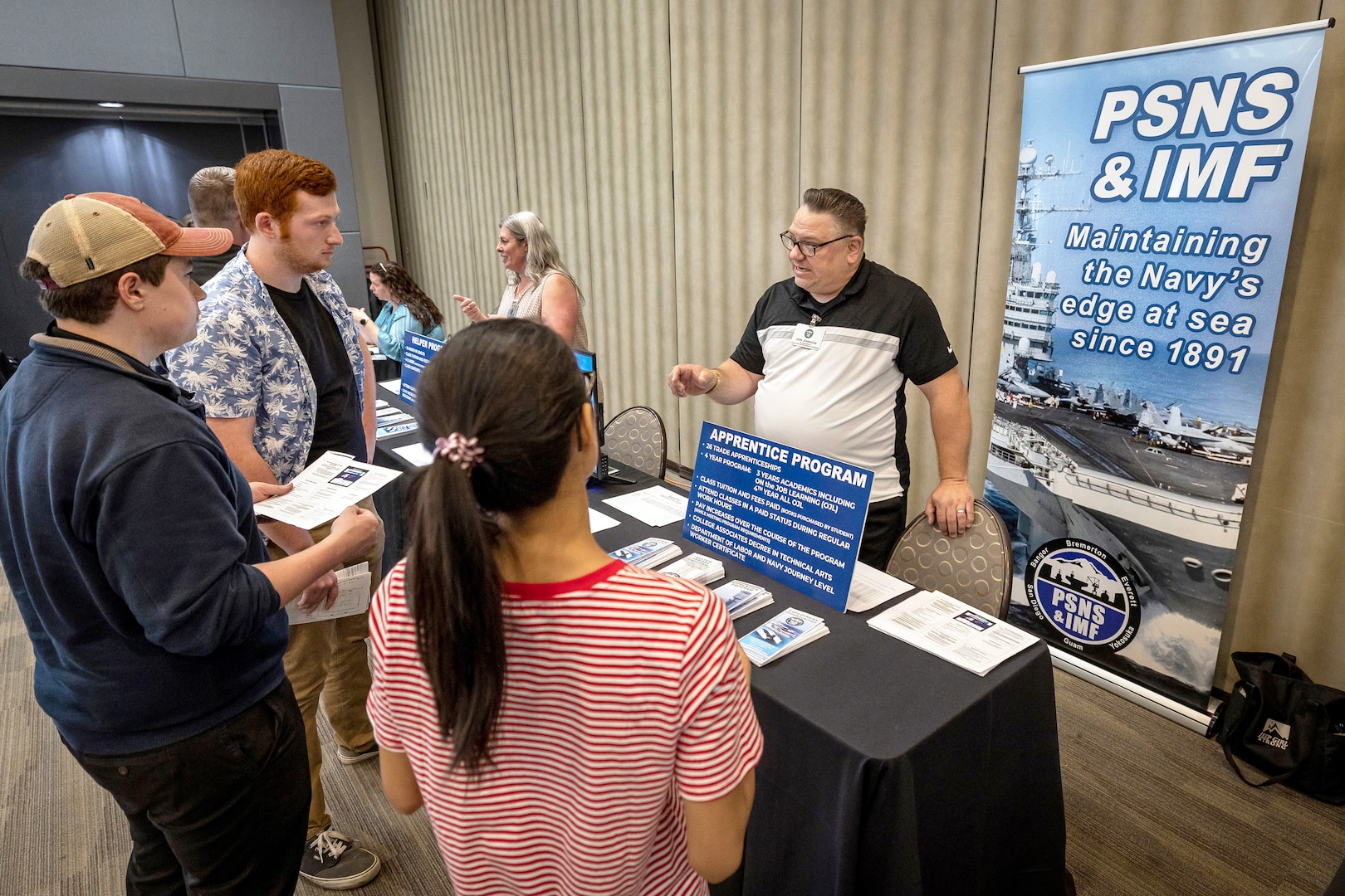 Dirk Johnson, work study and student program analyst, Puget Sound Naval Shipyard & Intermediate Maintenance Facility Apprentice Program, talks with a group of job candidates June 7, 2023, during the PSNS & IMF Hiring Fair at the Kitsap Conference Center in Bremerton, Washington. More than 400 job offers were extended to job seekers during the two-day event. (U.S. Navy photo by Scott Hansen)