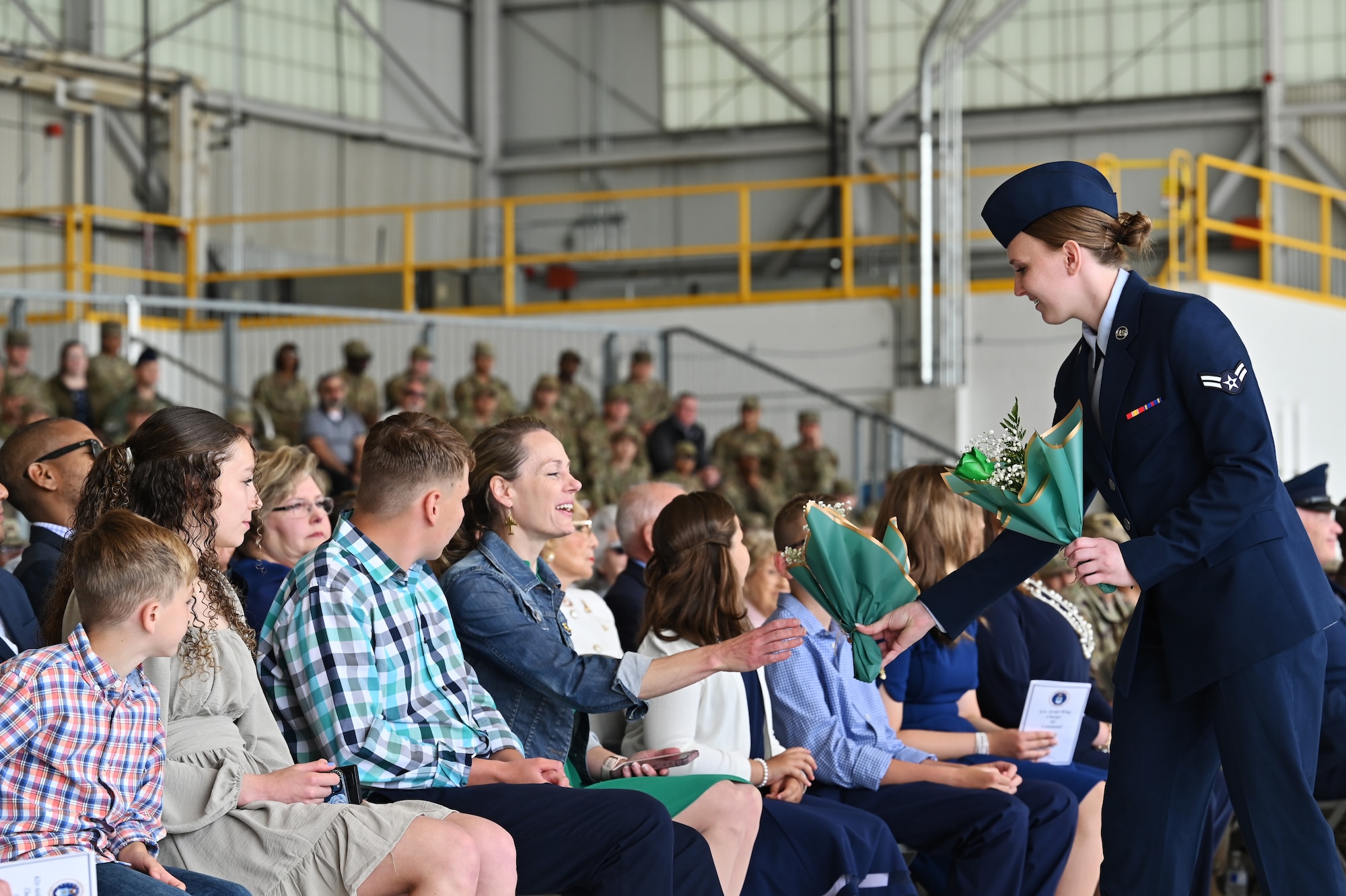 U.S. Air Force Airman 1st Class Erika Weatherly, financial analysis technician with the 62d Comptroller Squadron, presents gifts to the family of Col. David Fazenbaker, outgoing 62d Airlift Wing commander, during a change of command ceremony at Joint Base Lewis-McChord, Washington, June 21, 2023. Fazenbaker relinquished command of the 62d AW to Col. Sergio Anaya, former 62d Operations Group commander. (U.S. Air Force photo by Senior Airman Colleen Anthony)