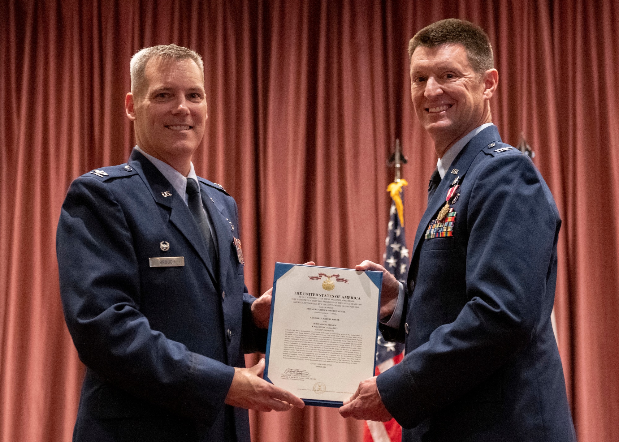 Col. Brad Brough, 374th Medical Group commander, hands Col. Craig Rhyne a meritorious service commendation during a change of command ceremony.
