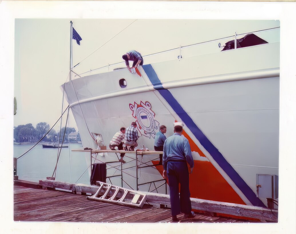 Crewmen of CGC Active paint the USCG stripe on the cutter's hull.  Scan of original photo provided by Active's CO in 2023.