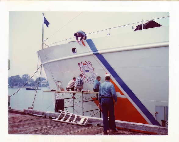 Crewmen of CGC Active paint the USCG stripe on the cutter's hull.  Scan of original photo provided by Active's CO in 2023.