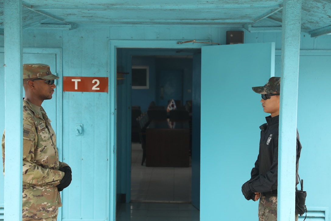 Two soldiers stand guard on opposite sides of an open doorway.