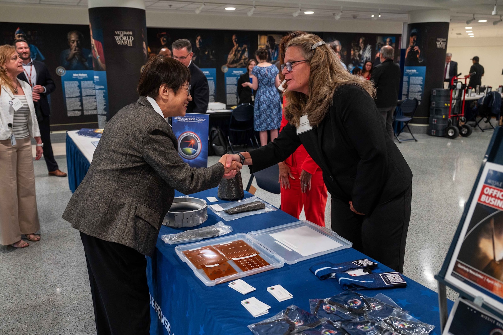 Two people shake hands over a table.