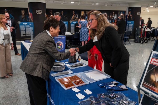 Two people shake hands over a table.