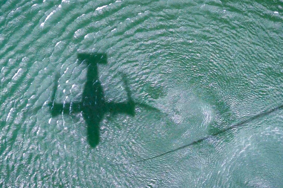 The shadow of an aircraft over a body of water.