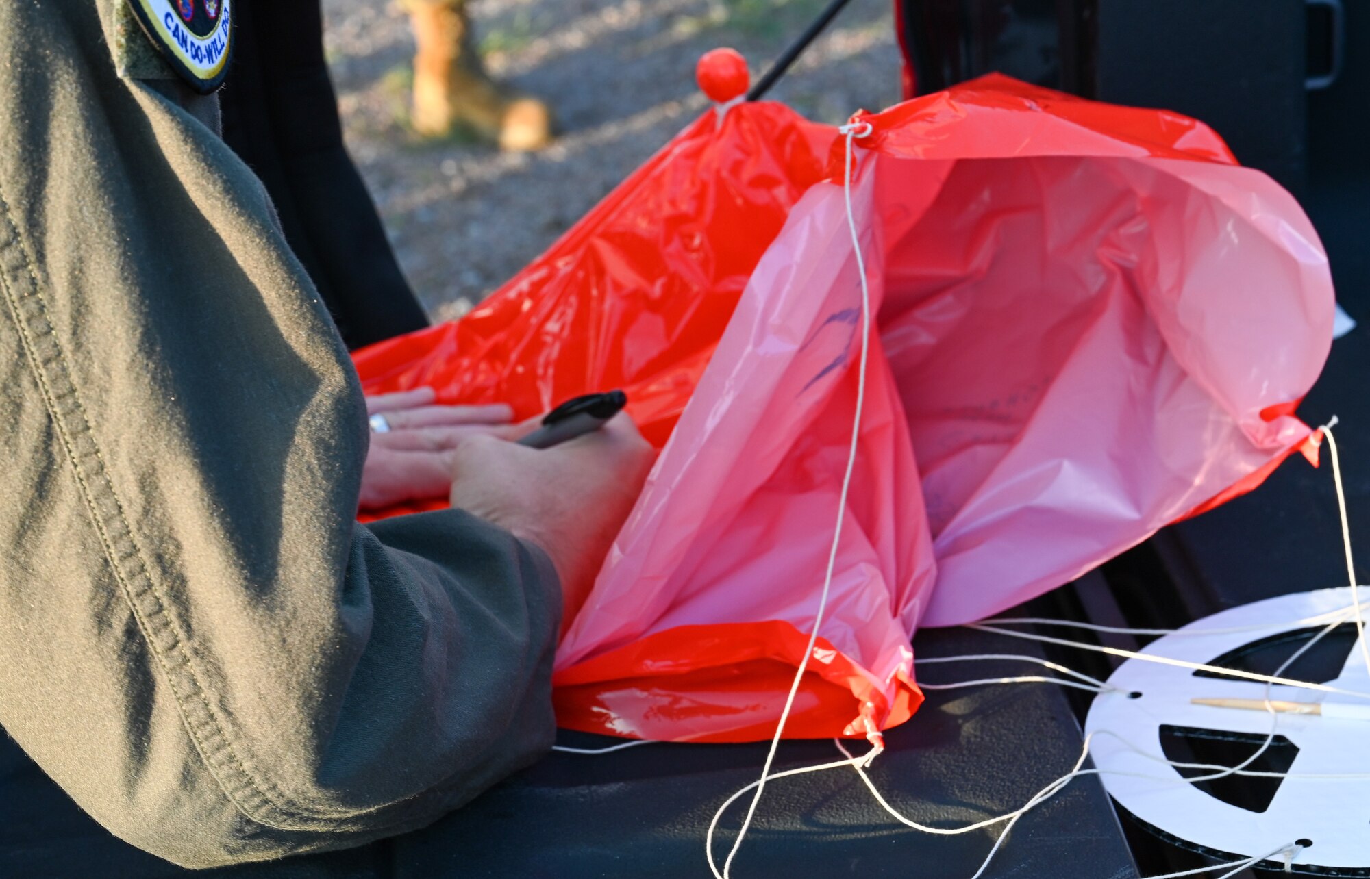 U.S. Air Force Col. Scott Linck, 97th Operations Group commander, signs a weather balloon parachute at the Sooner Drop Zone, June 15, 2023. Weather balloons are used throughout the Department of Defense, National Weather Service, and National Oceanic and Atmospheric Administration to provide accurate readings of upper levels of the earth’s atmosphere. (U.S. Air Force photo by Airman 1st Class Heidi Bucins)