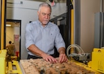 A man in a blue shirt looks at a large try of glass slides in a try.