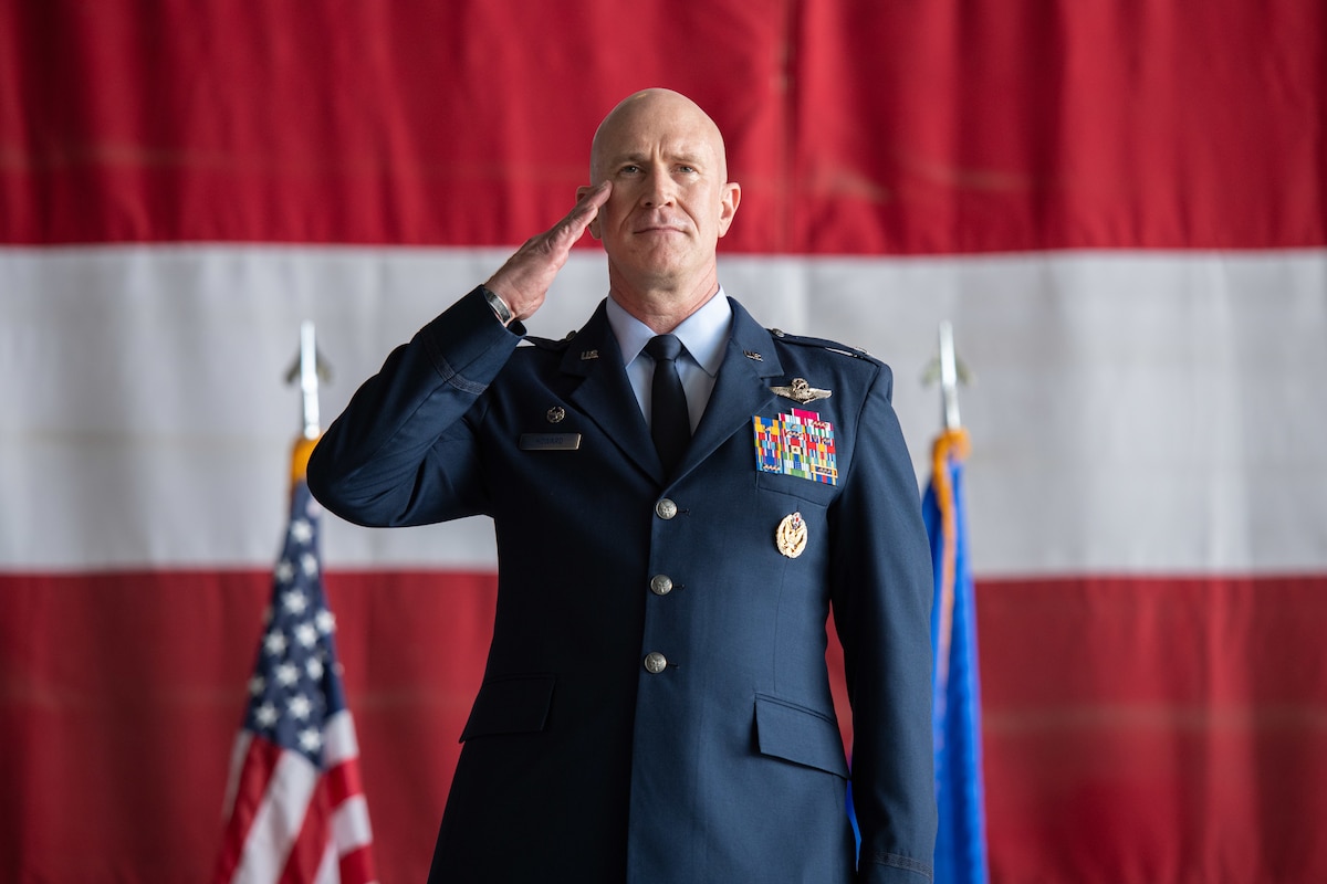 Man in uniform saluting in front of huge U.S. flag back drop