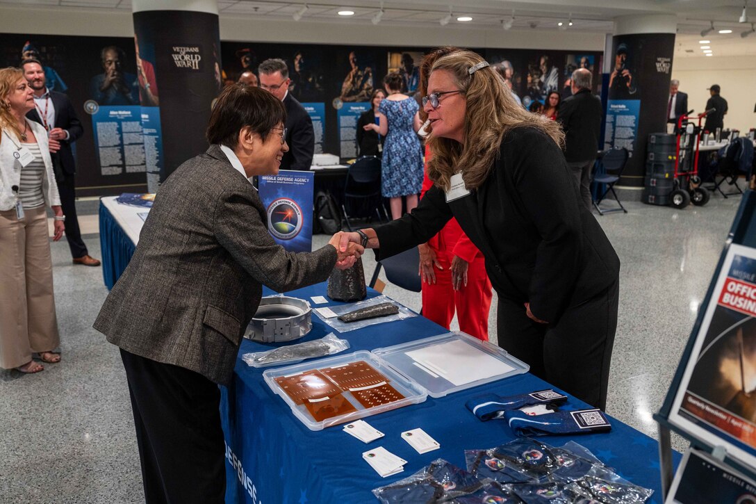 Two people shake hands over a table.