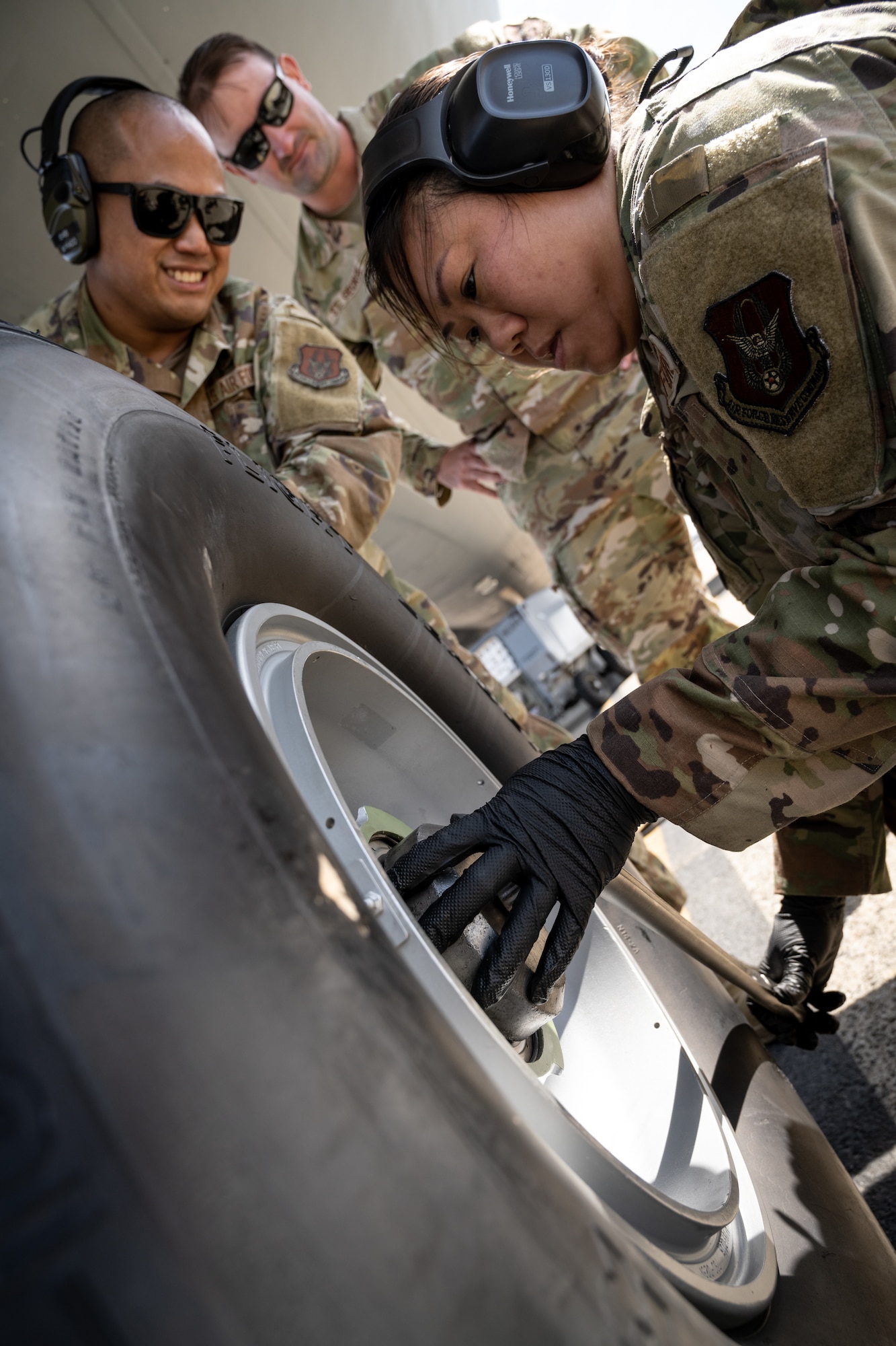 Three Airmen change a tire of an aircraft